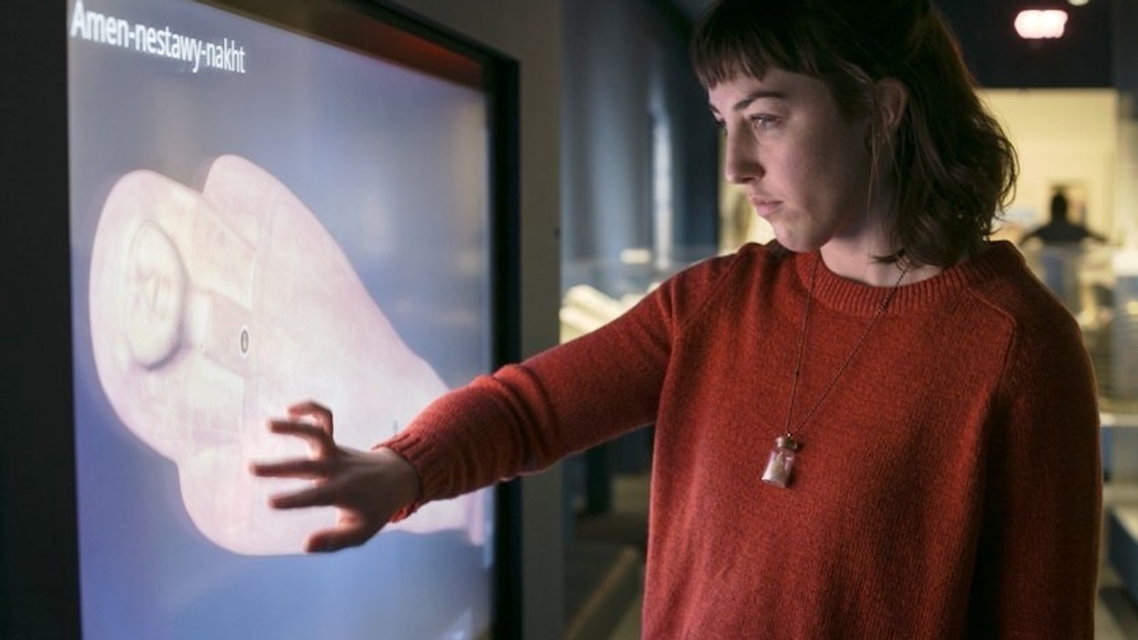 woman places hand on interactive 3D screen showing egyptian mummy at saint louis art museum