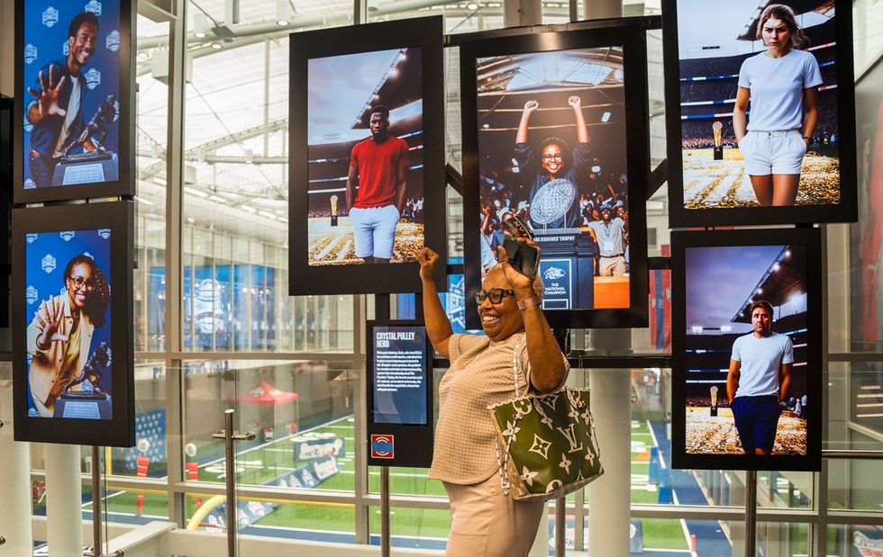 Woman posing excitedly by sports-themed photo display in a bright, modern venue.