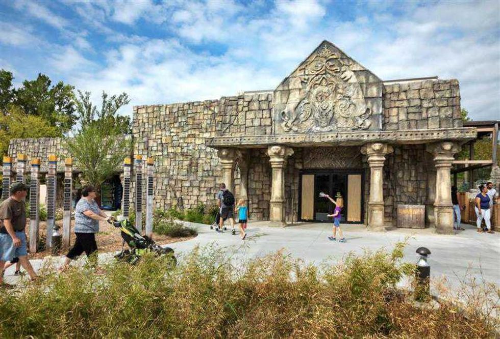 woman pushes pram outside temple at PGAV-designed Lost Kingdom exhibit opens at Tulsa Zoo