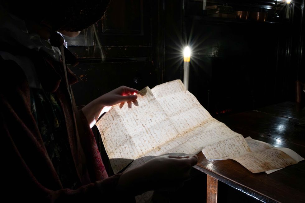 Woman reading by candlelight in the dark at the Wordsworth Grasmere museum Gothic exhibition