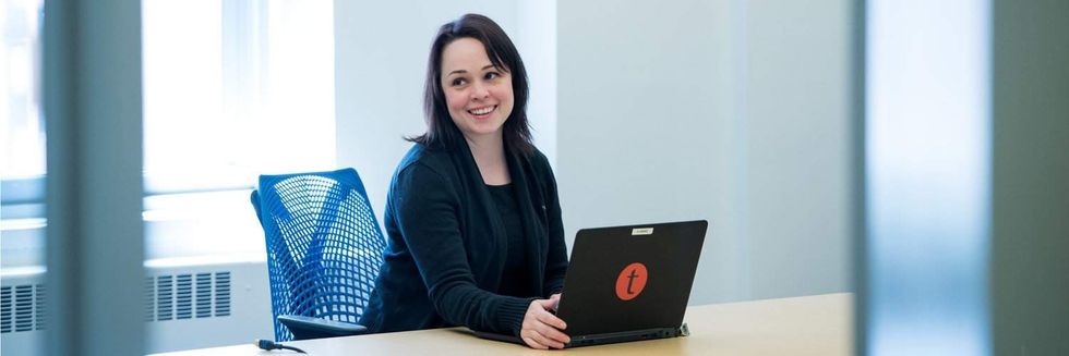 Woman sat at desk Tessitura Network laptop