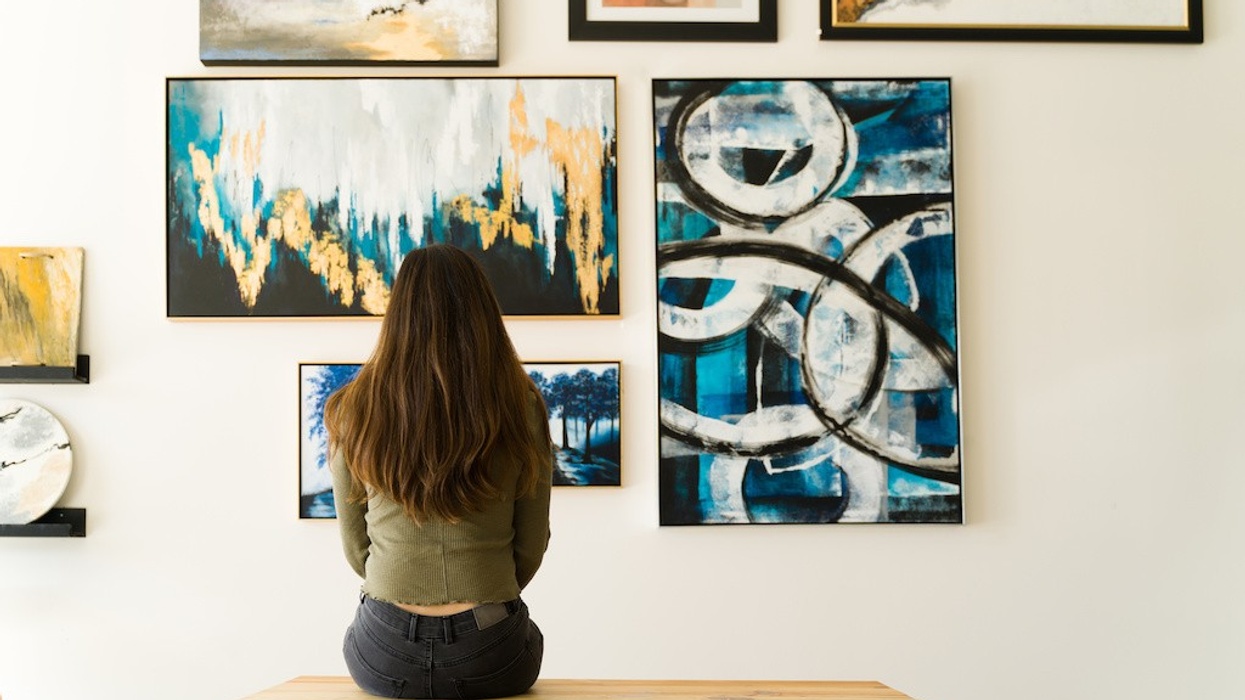 Woman sitting on a bench, viewing abstract art in a gallery.