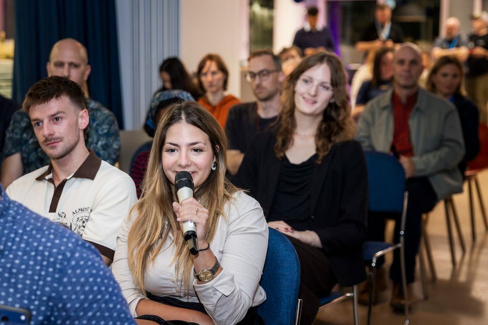 Woman speaking into mic in a seated audience.