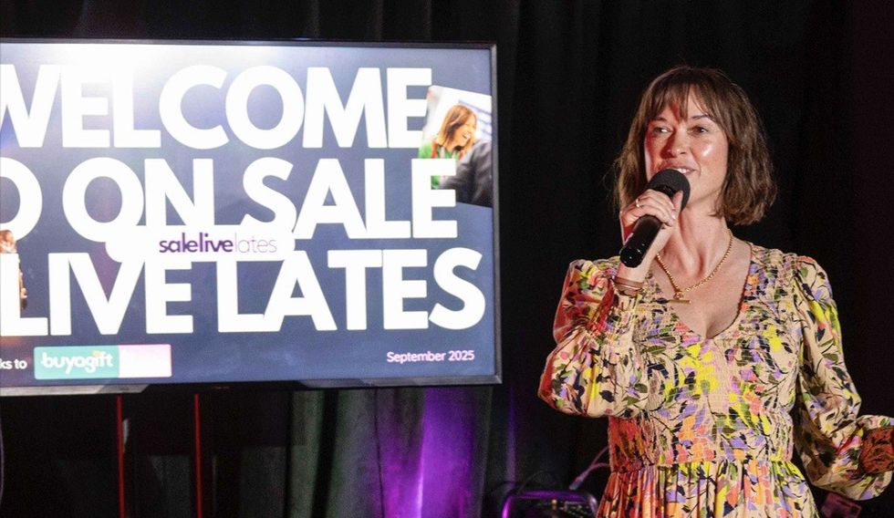 Woman speaking on stage next to "WELCOME TO LIVE LATES" sign.