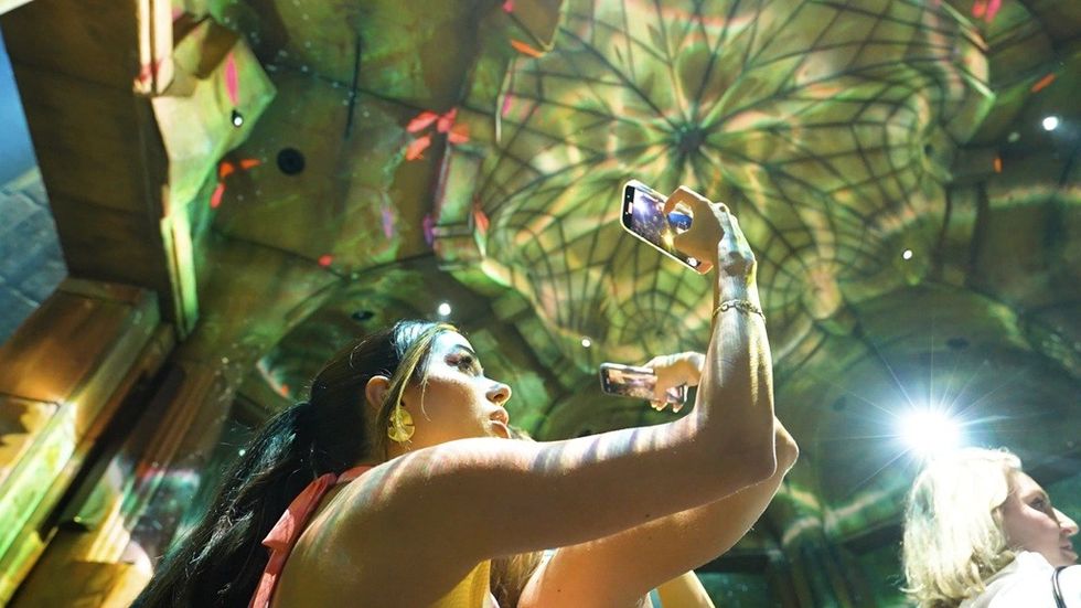 Women take photos of a colorful, illuminated ceiling design.