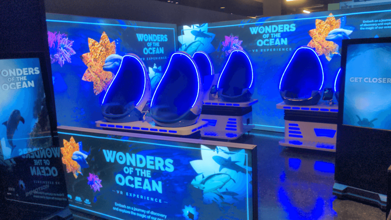 "Wonders of the Ocean VR pods glow blue in an interactive exhibit space with marine life graphics."