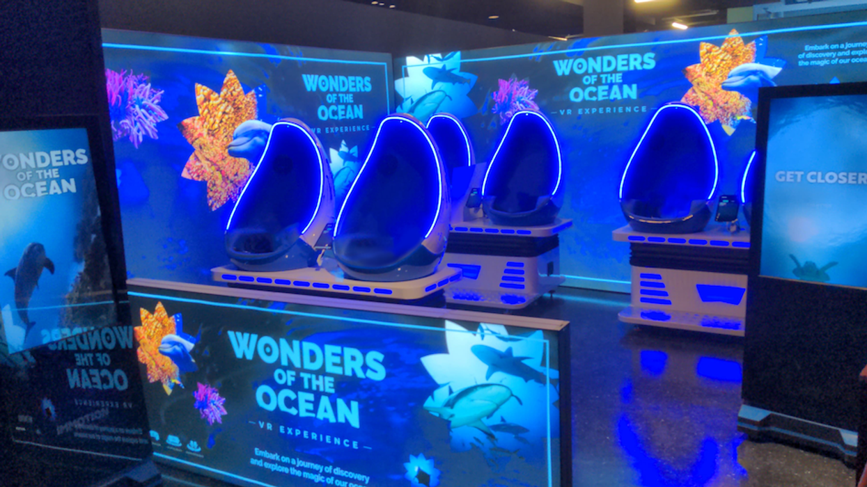 "Wonders of the Ocean VR pods glow blue in an interactive exhibit space with marine life graphics."