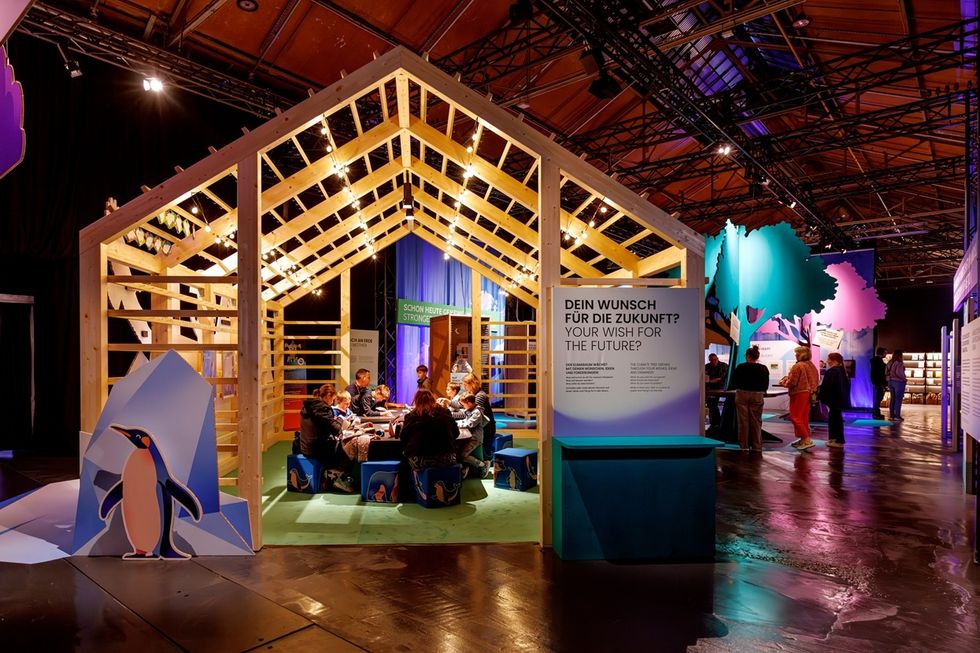 Wooden structure with people seated inside at a conference, surrounded by colorful decor in the immersive '\u200bPolar Experience'