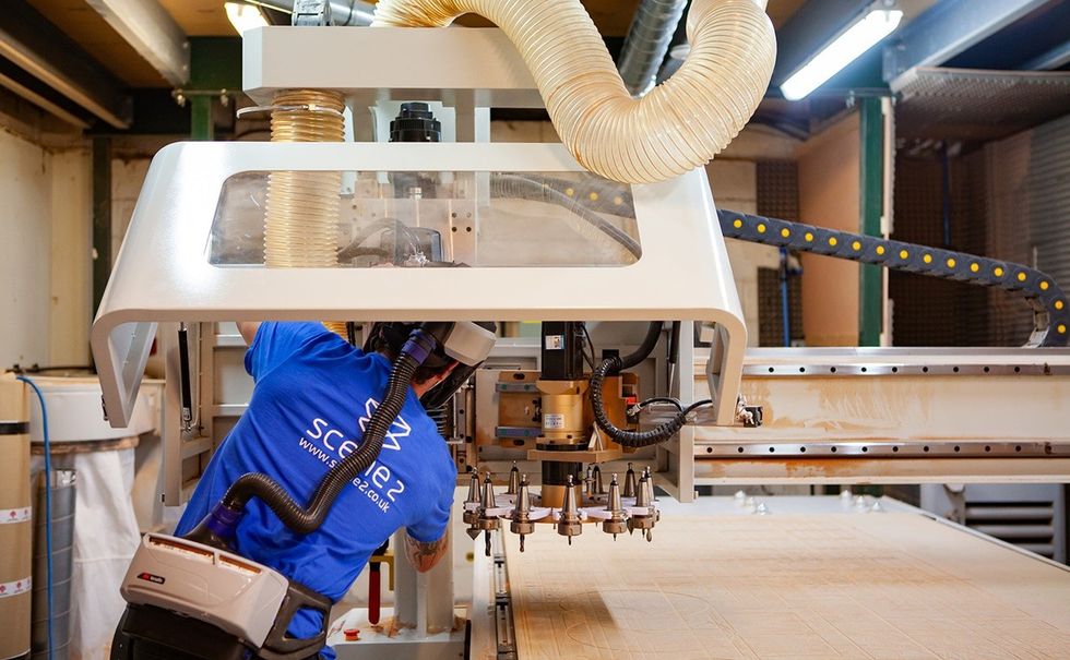 Worker operating a large CNC machine in an industrial setting.