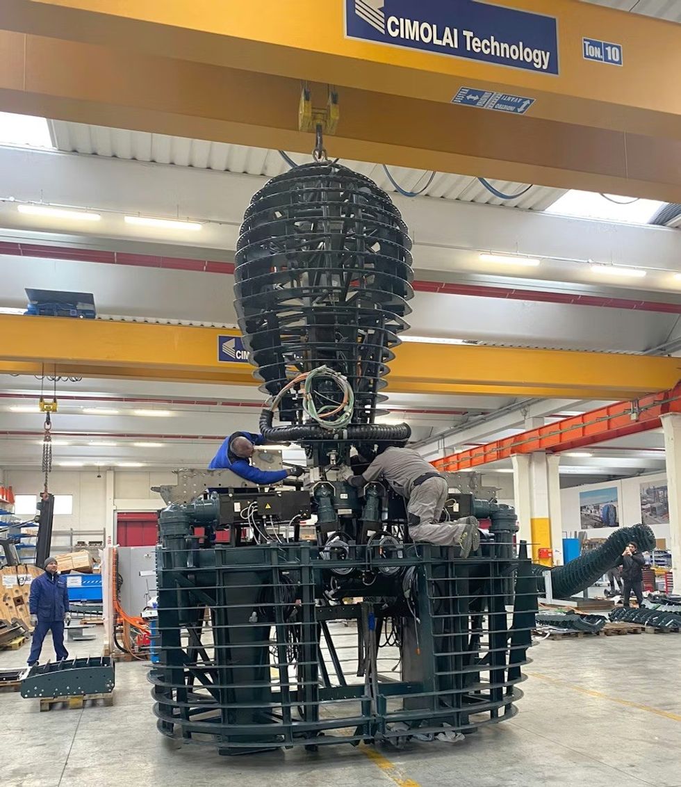 Workers assembling the Giant under a large industrial crane indoors.