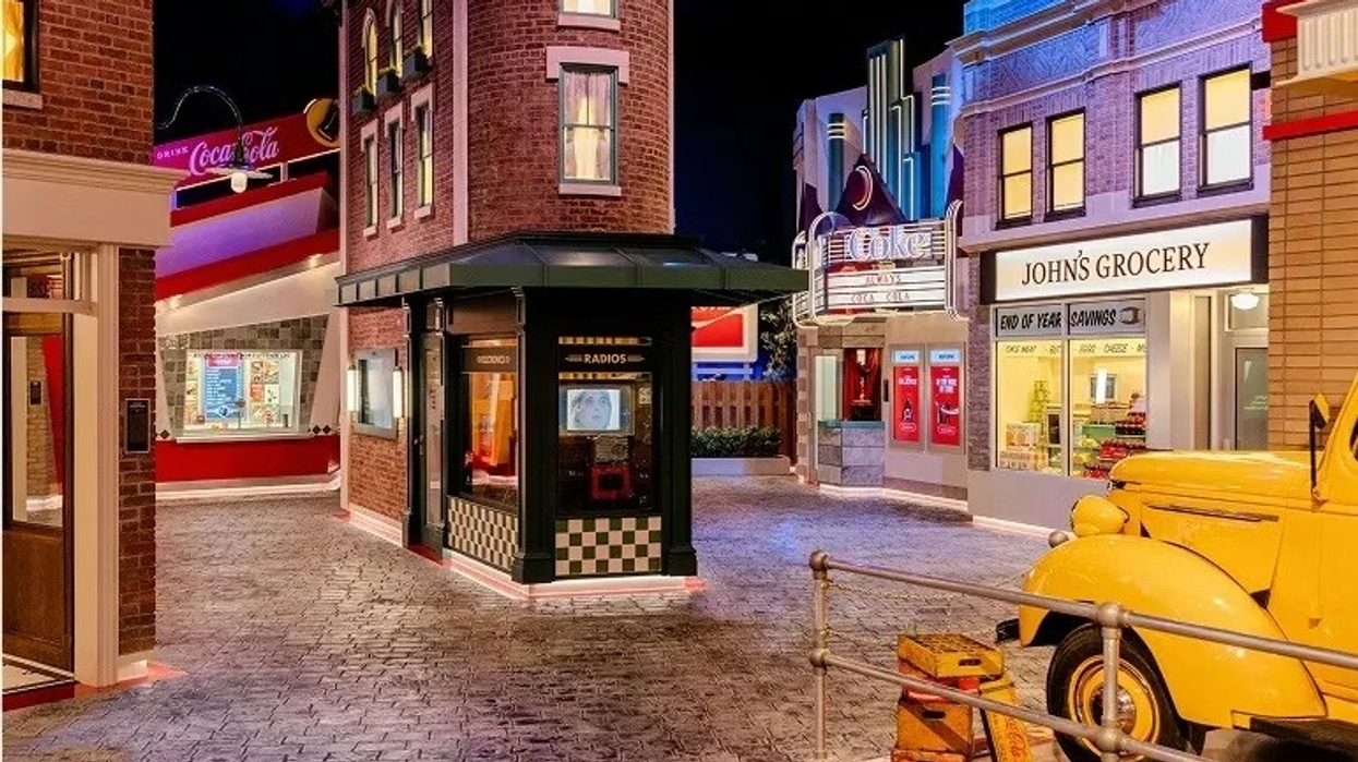 World of Coca-Cola: Coke Stories. Vintage street scene with a Coke sign, radio store, grocery, and yellow truck.