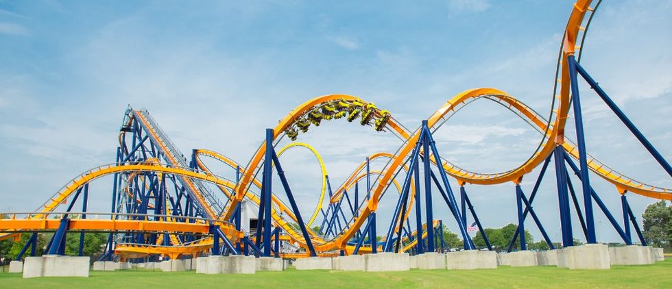 Yellow and blue roller coaster with loops under a clear blue sky.