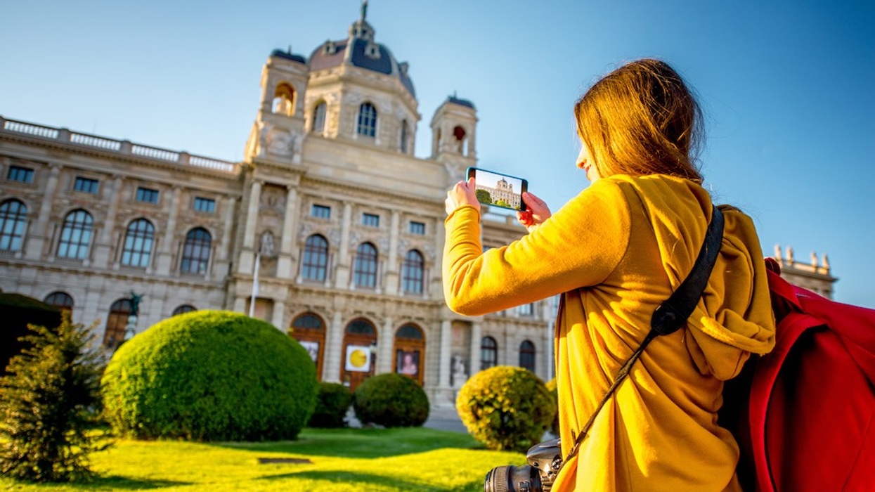 Young female tourist photographing with smart phone museum of Art History in Vienna. best ticketing