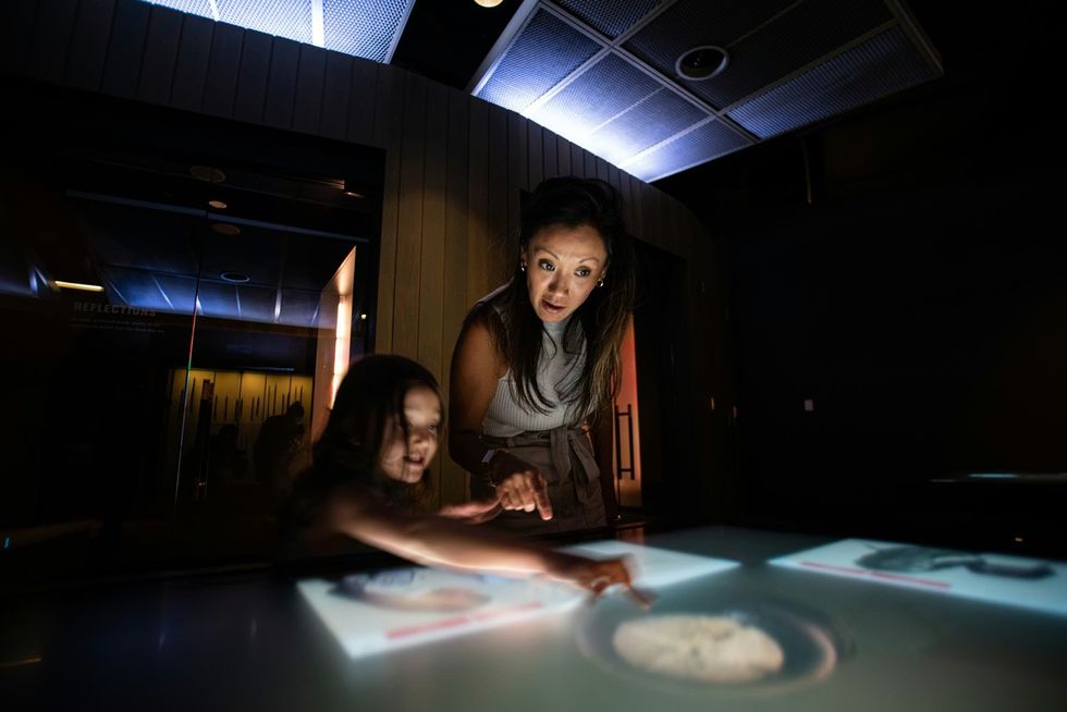 Young girl and woman interact with an interactive table at the National WWI Museum and Memorial: Encounters Exhibition
