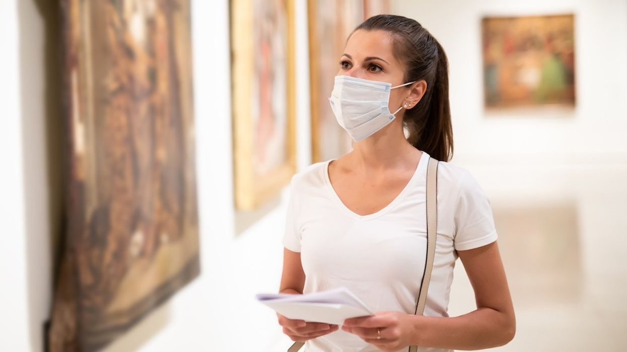 Young woman wearing face mask observing artworks in museum, new normal due to coronavirus outbreak