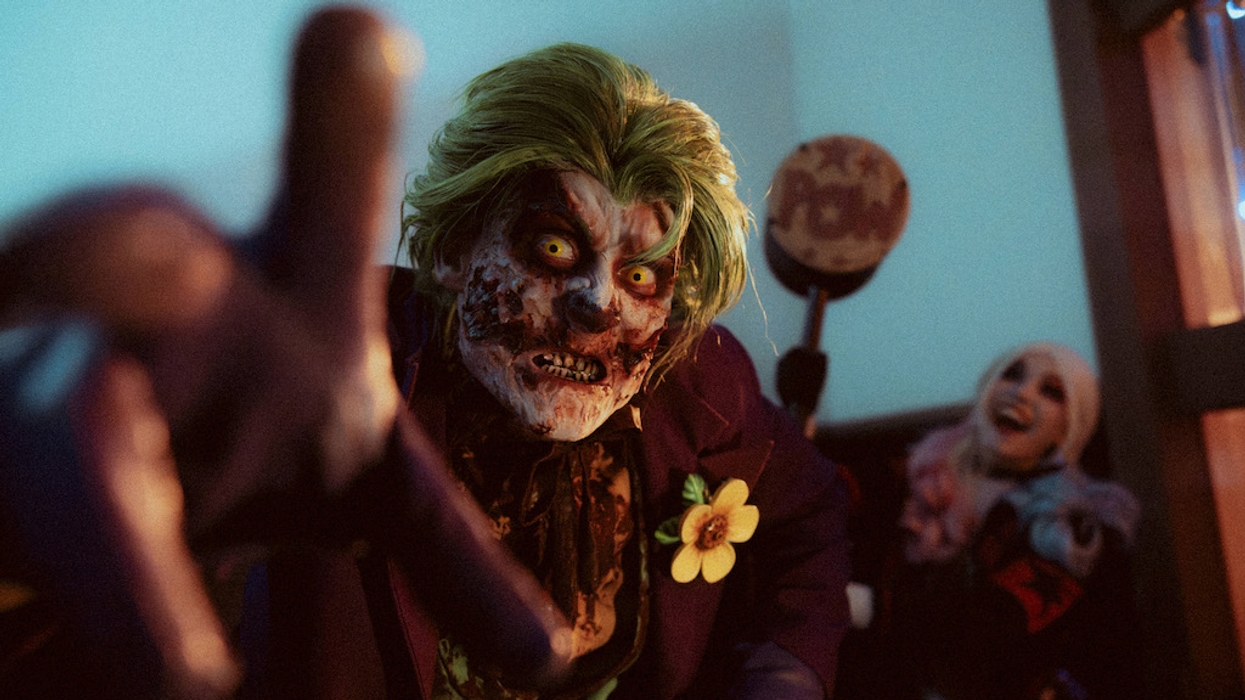 Zombie-like character in a green wig, with another person laughing in the background.