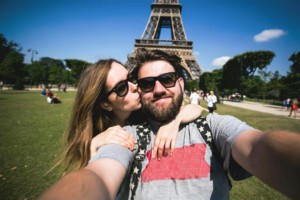 man and woman take selfie at eiffel tower