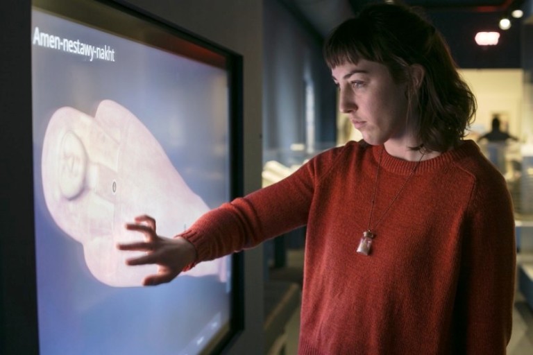 woman places hand on interactive 3D screen showing egyptian mummy at saint louis art museum