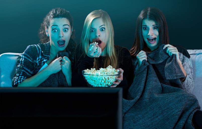 girls eating popcorn and watching horror film