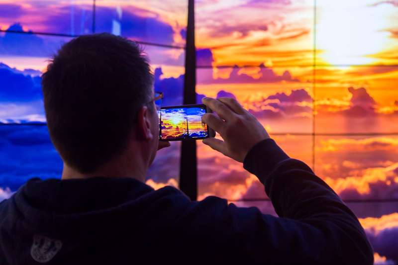 ise 2018 man infront of sunset digital led screen with smartphone