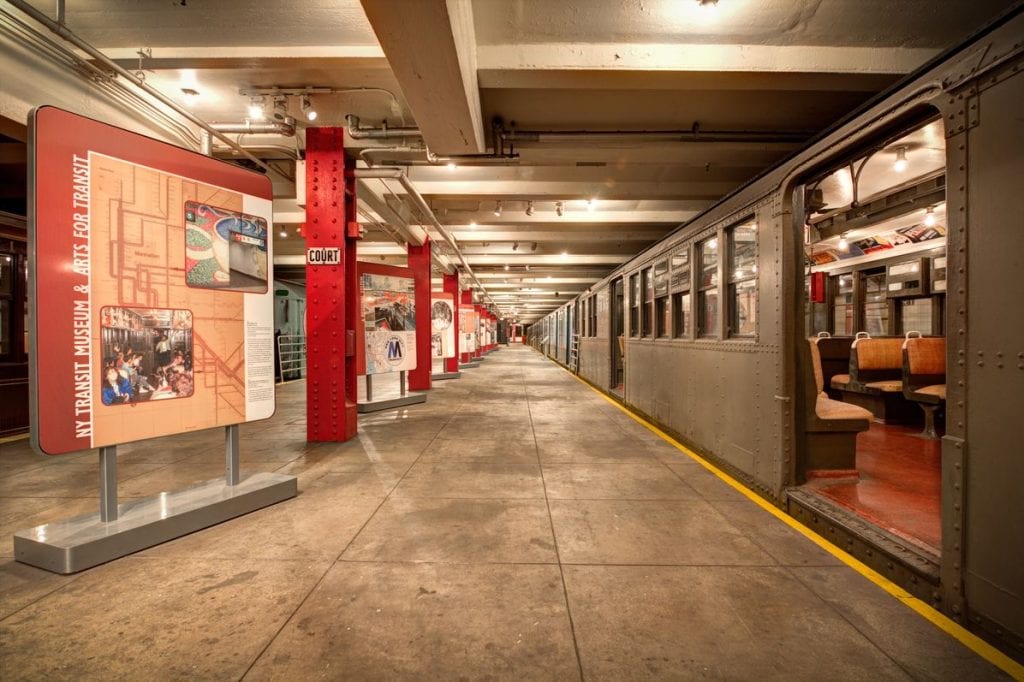 Exhibition on the left side of the platform of the New York Transit Museum, with a train carriage on the right