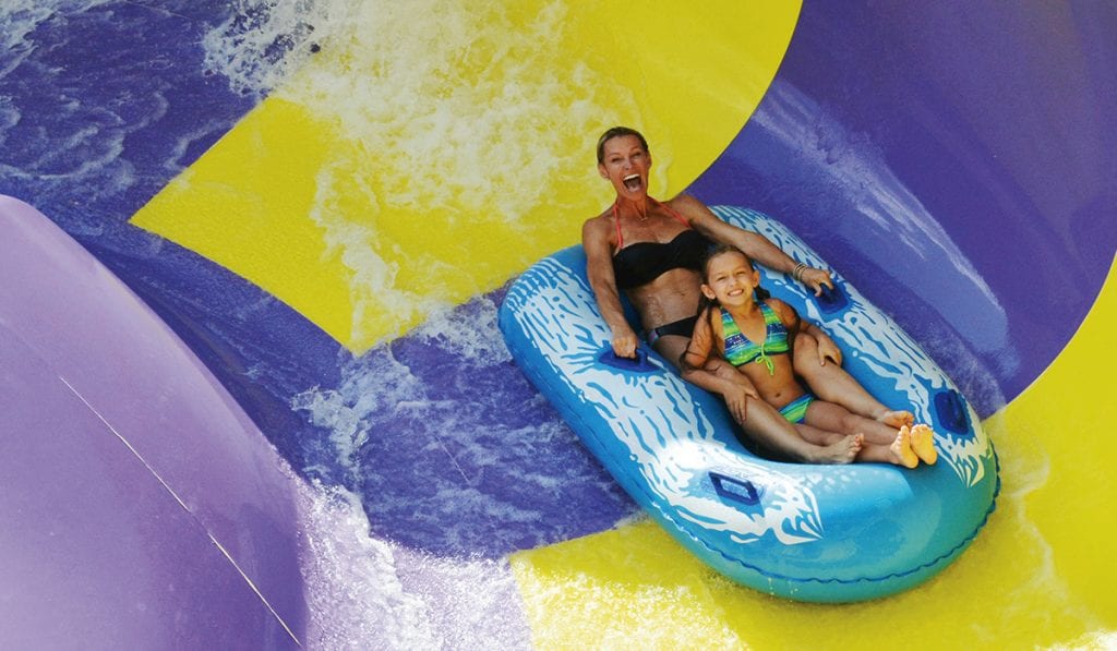 Mother and daughter on a two person raft taking a turn on a circular bowl on the water slide