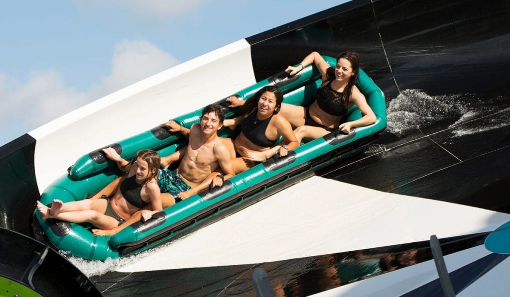 Close-up image of four teenagers riding on a raft riding the side of a flying saucer