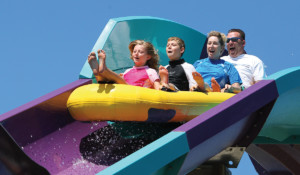 4 Passengers on a raft going down a purple and blue water coaster