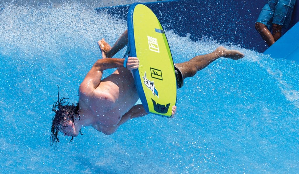 Man diving head first into a wave with a surfboard