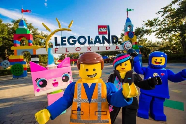 Unikitty, Emmet, Wyldstyle and Benny from THE LEGO MOVIE WORLD posing in front of Legoland Florida entrance