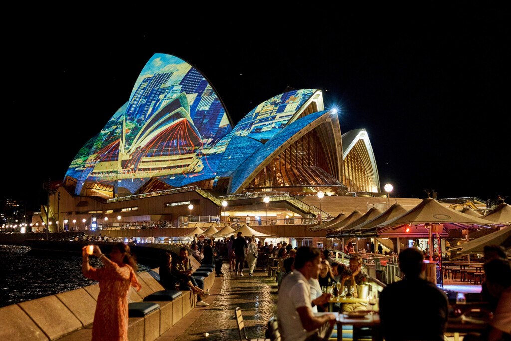 Image of the Sydney Opera House's 'From the Sails: Light Year's' projection-mapping on the western sails, viewed from the Sydney Harbour Restaurants. Experience Design by Art Processors.