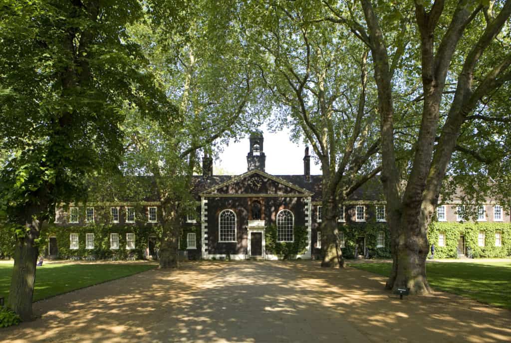 A wide-angle shot of the Museum of the Home Geffrye almshouses in the sunshine. The view is down the central path towards the exterior of the Chapel, one of the museums documenting the pandemic