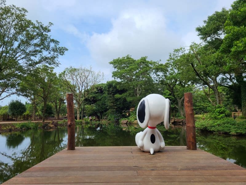 Snoopy statue sitting at edge of lake