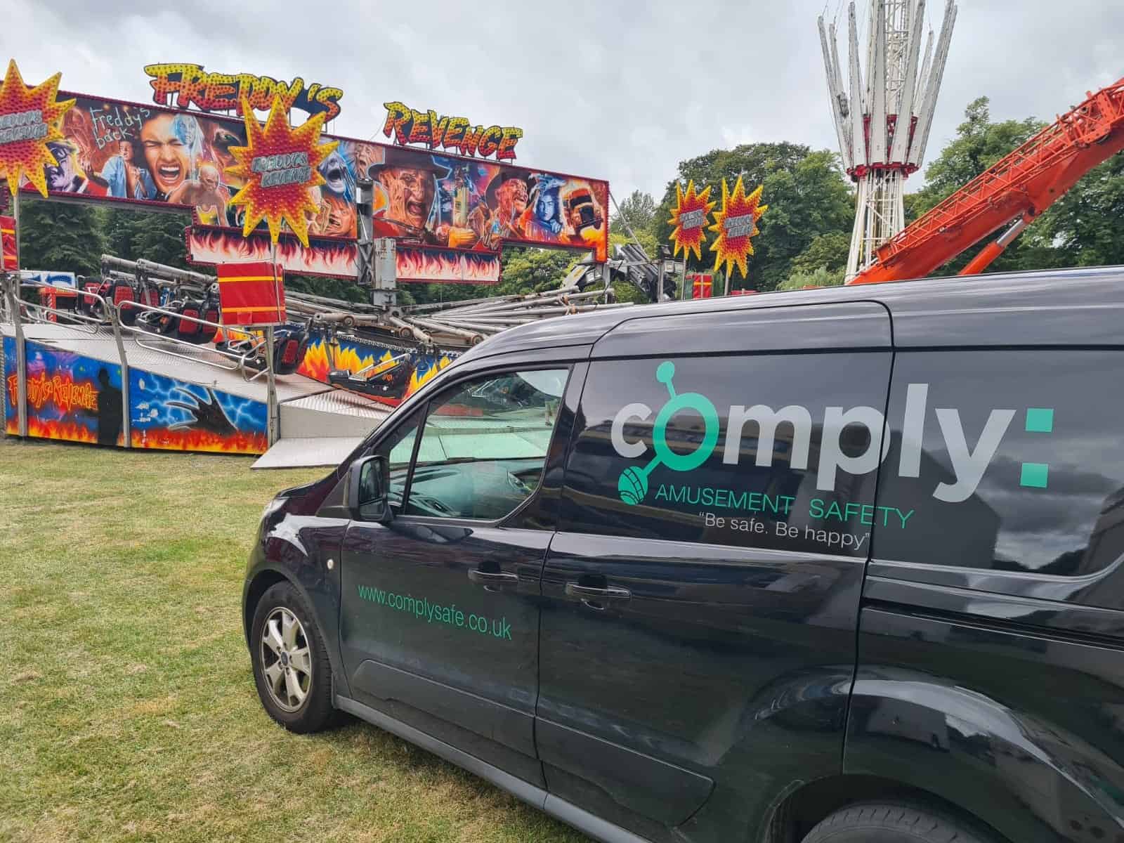 Black van with comply logo on side at theme park