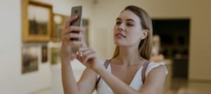 Woman photographing painting in museum mobile phone