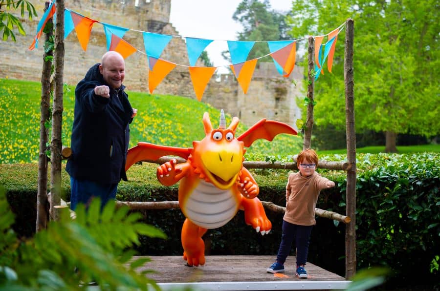 Children poses next to a Zog dragon statue at Warwick Castle