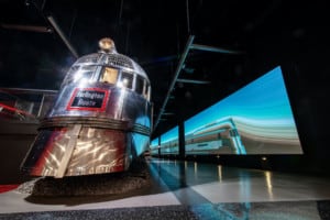 Blue LED displays down hallway with chrome passenger train at left