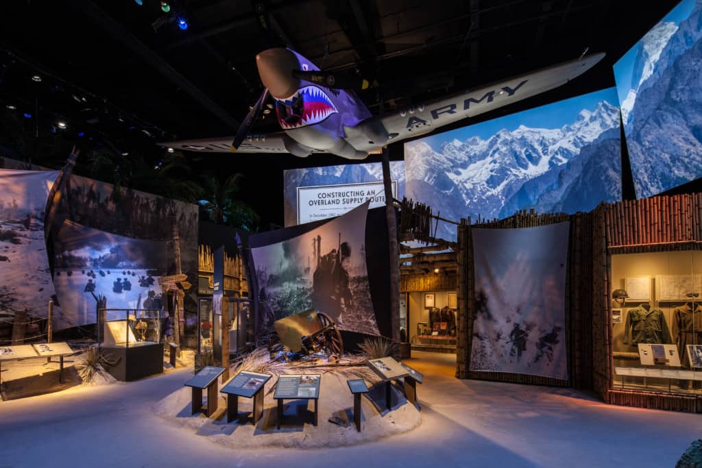 This is an exhibit from the WWII Museum including an overhanging plane and AV screens.