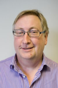 Jim Griffiths headshot man wearing glasses in a purple stipe shirt