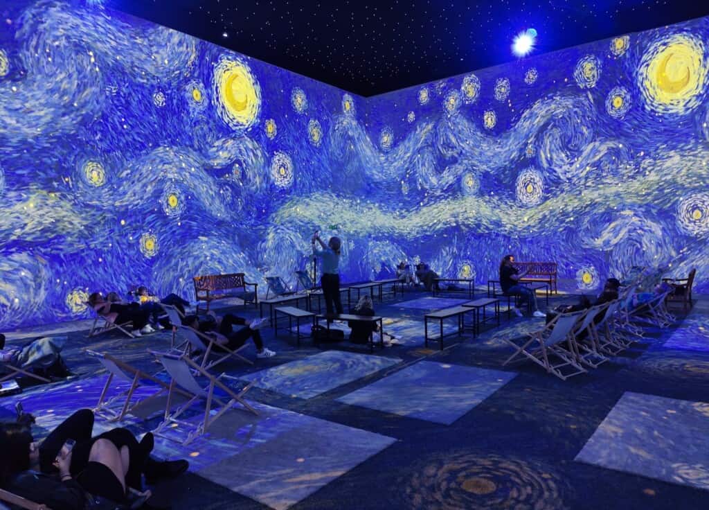 People sitting in immersive van gogh exhibition