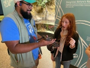 Children's Aquarium Dallas staff member shows snake to young visitor