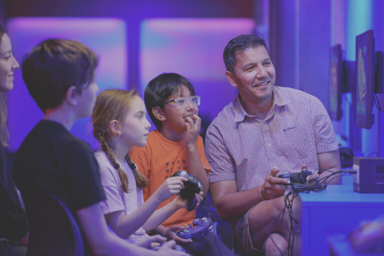 Families and friends enjoying a 4-player game in Power Up, the Science Museum’s hands-on gaming experience