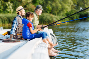 Fishing all together. Men of three generations enjoying morning while fishing all together