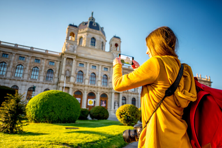 Young female tourist photographing with smart phone museum of Art History in Vienna. best ticketing