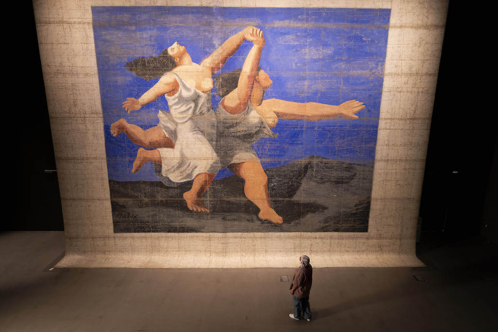 The largest Picasso work in the world,
the 1924 front stage cloth for the Ballets
Russes’ production, Le Train Bleu, at
V&A East Storehouse. Image by David
Parry/PA Media Assignments. Pablo
Picasso, Le Train Bleu front stage cloth,
1924 © The estate of Pablo Picasso