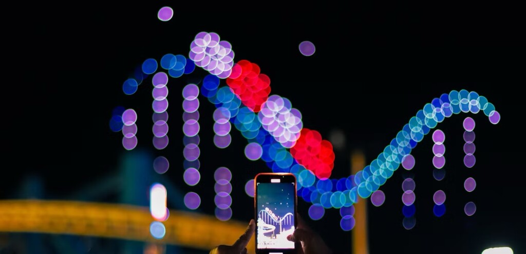 Aerial Illuminations drone show. The drones are forming the shape of a roller coaster drop. Some is recording the show on their phone.