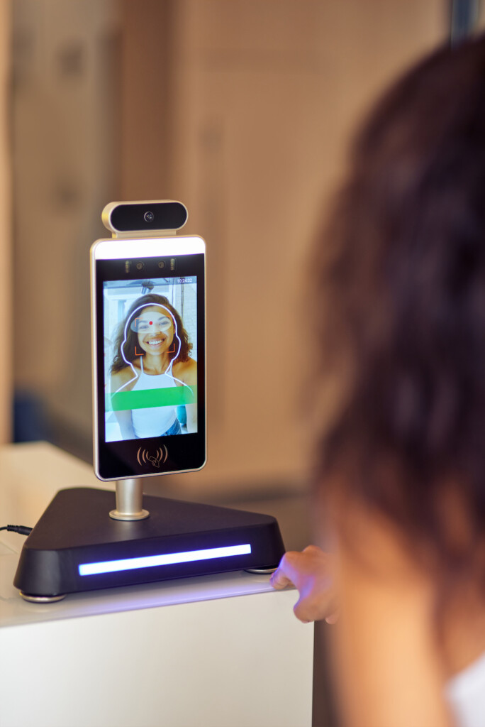 Modern security system. Rear view of female office worker using face recognition at work, business and identification technology hyper-personalization